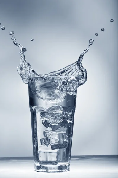 Frischwasser Spritzt Aus Einem Glas Mit Eiswürfeln Über Dem Hintergrund — Stockfoto