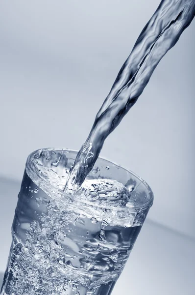 Água doce derramando em um copo — Fotografia de Stock