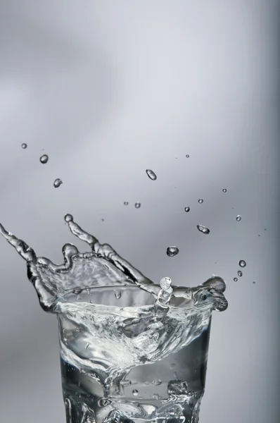Fresh water splashing out of a glass with ice Stock Image