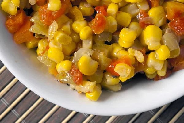 stock image A salad of corn, peppers and tomatoes on a background of bamboo.