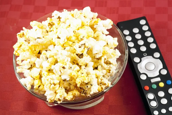 stock image Bowl of popcorn on the table and remote control for TV