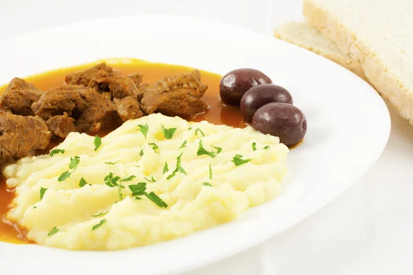 Goulash with potato puree, olives and bread — Stock Photo, Image