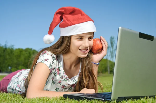 Meisje met laptop liggend op een gras — Stockfoto