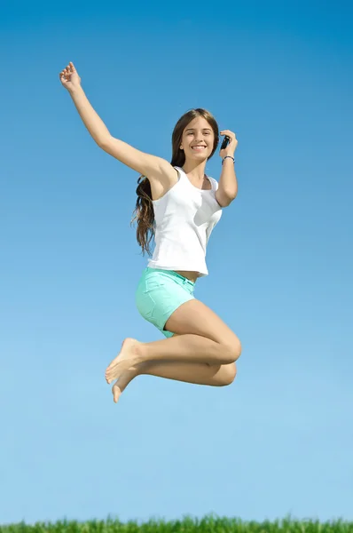 Flickan hoppar med mobiltelefon Stockbild