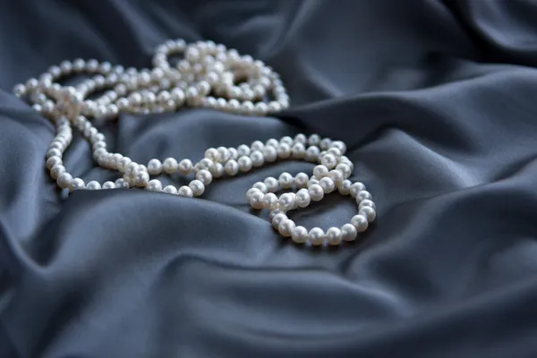 Weiße Perlen auf blauem Satin — Stockfoto