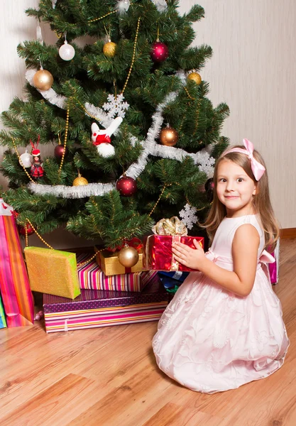 Девушка с подарками возле елки — стоковое фото
