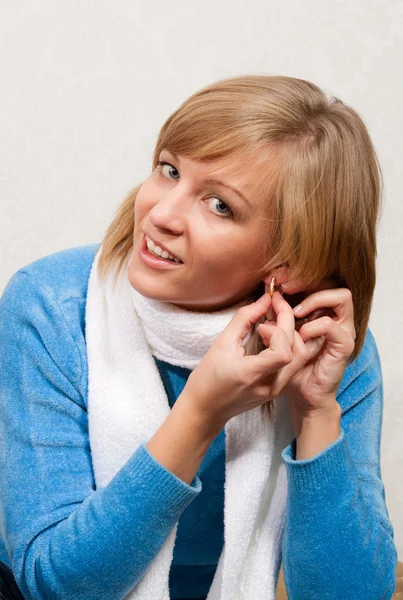 Jonge vrouw legt op oor-ringen — Stockfoto