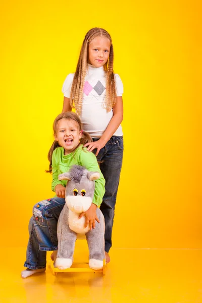 在黄色背景上的两个快乐女孩 — 图库照片