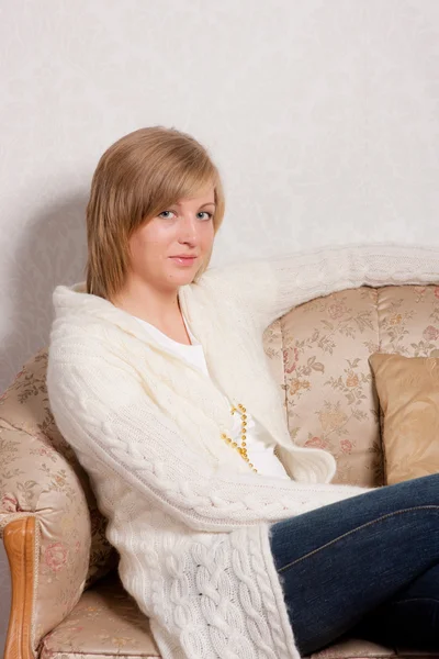 一个年轻女子坐在柔软的沙发上 — 图库照片