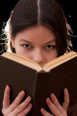 Charming young woman looking above a book clipart