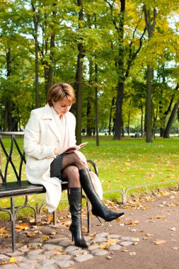 Charming young woman reading a book clipart