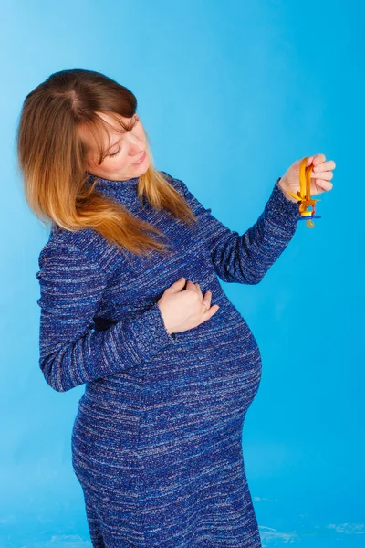 婴儿奶嘴在蓝色背景上的美丽孕妇 — 图库照片