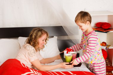 A careful boy brought breakfast to the mother in a bed clipart