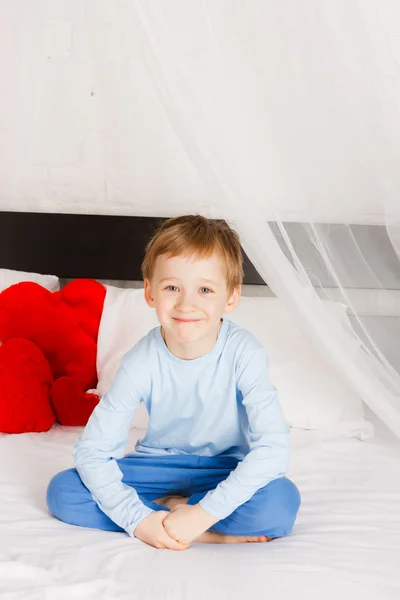微笑的男孩坐在一张床在舒适的情况 — 图库照片