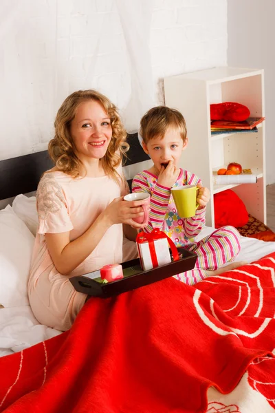 Donna con suo figlio colazione in un letto — Foto Stock