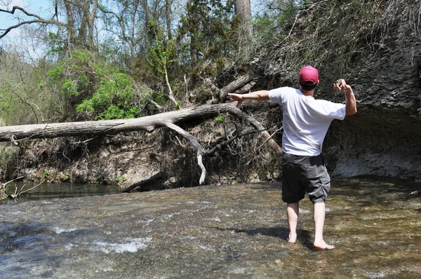 El hombre lanza piedras al puente del tronco — Foto de Stock