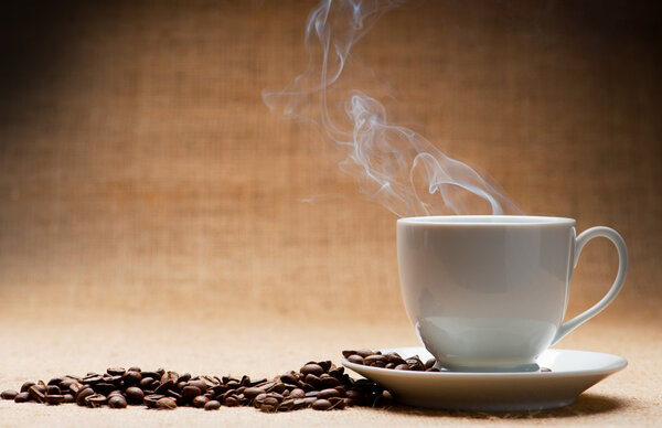 Чашка горячего кофе о пароме и зерно кофе на гранже
