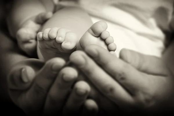 Yetişkin ellerinde bebek ayaklar. eski siyah beyaz — Stok fotoğraf