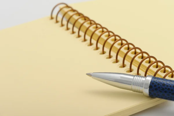 Ручка и блокнот на спирали с желтой бумагой — стоковое фото