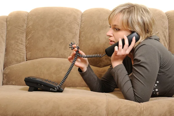 Kvinnan talar via telefon på en soffa — Stockfoto