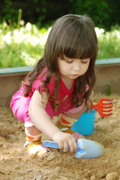 La chica jugando a una caja de arena — Foto de Stock
