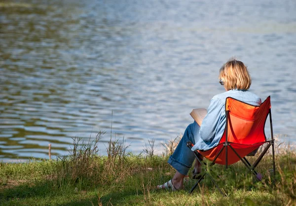 Жінка читає книгу на березі озера — стокове фото