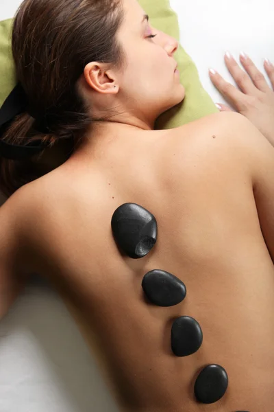 Frau legt sich mit heißen Steinen auf den Rücken — Stockfoto
