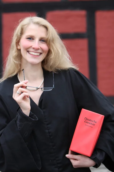 Amistoso estudiante de derecho sonriente o abogado con libro de derecho rojo bajo h — Foto de Stock