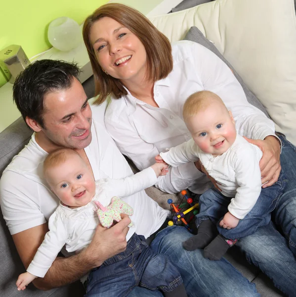 Familia joven y feliz con dos hijos y bebés gemelos en casa —  Fotos de Stock