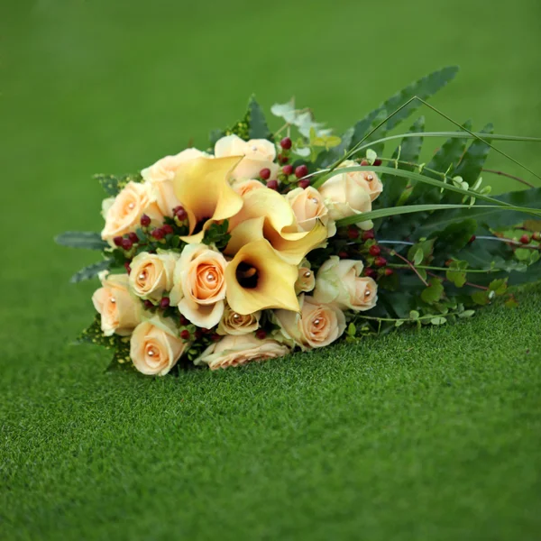 黄色卡拉斯和在绿色的草坪上玫瑰的香味 — 图库照片