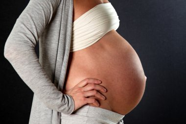 Koca bir göbek ile hamile kadın fotoğrafının yan-