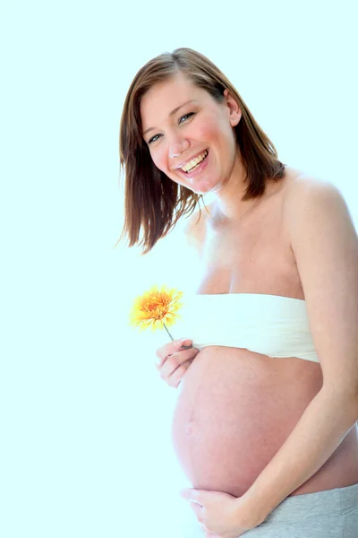妊娠中 赤ちゃん腹の女性カメラに向かって見える幸せな笑顔と花を保持 — ストック写真