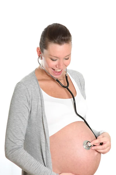 Счастливая беременная женщина со стетоскопом на животе — стоковое фото