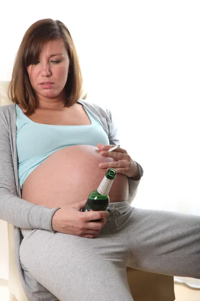 Беременная женщина курит сигарету и пьет алкоголь — стоковое фото