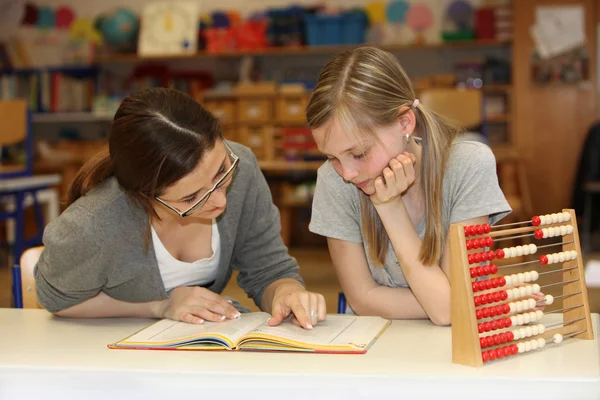 Professora e estudante no livro didático da escola aprendendo juntos — Fotografia de Stock