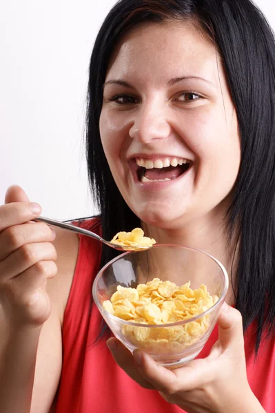 Una giovane donna che mangia corn flakes da una ciotola — Foto Stock