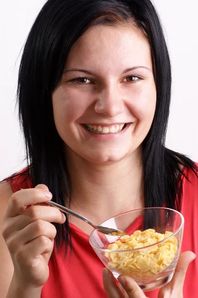 Une jeune femme mangeant des flocons de maïs dans un bol — Photo