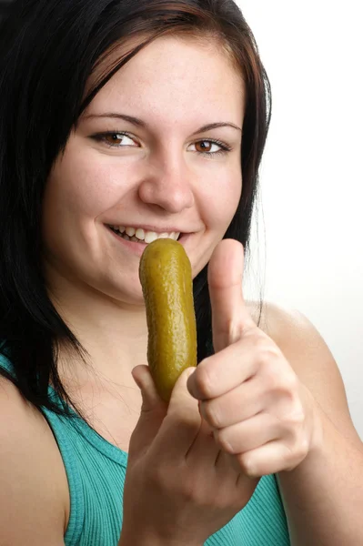 Una mujer joven comiendo un pepinillo orgánico — Foto de Stock