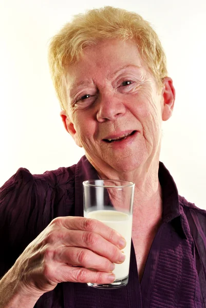Uma mulher de idade está segurando um copo de leite — Fotografia de Stock
