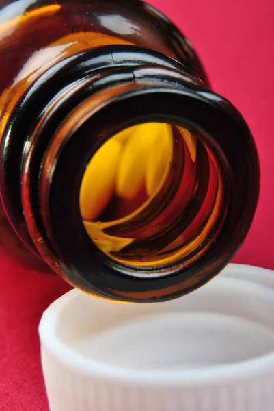 Una bottiglia di pillola marrone e alcune pillole — Foto Stock