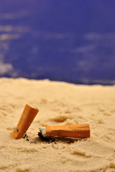 Algunas puntas de cigarrillos en una playa de arena — Foto de Stock