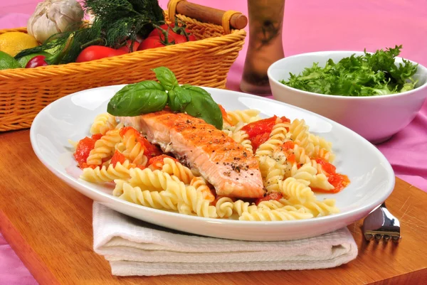 Grilled organic salmon on some tomato pasta — Stock Photo, Image