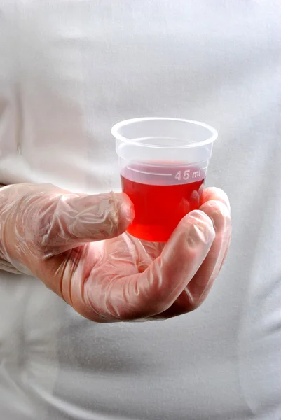 Медицинский персонал в одноразовых перчатках дает жидкое лекарство — стоковое фото