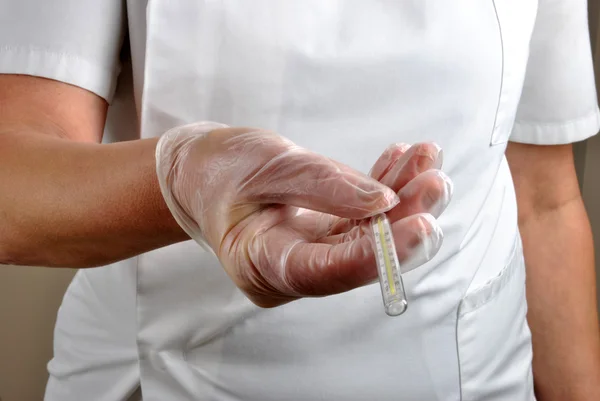 Tek kullanımlık eldiven ile sağlık personeli analog klinik derece verir — Stok fotoğraf