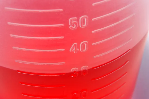 30 мл красной жидкости в качестве лекарства в небольшом контейнере — стоковое фото