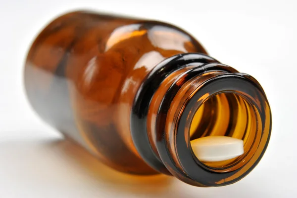 Bruine medische fles en een witte pil — Stockfoto
