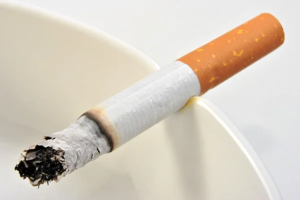 Een ongezonde sigaret in een glas asbak — Stockfoto