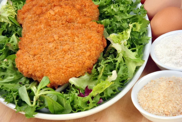 Ekmekli göğsü bir plaka üzerinde organik salata ile — Stok fotoğraf