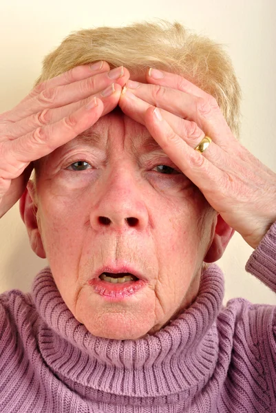 Uma mulher velha tem uma dor de cabeça dolorosa — Fotografia de Stock