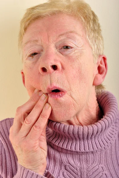 Eine alte Frau hält ihren schmerzhaften Kieferknochen — Stockfoto